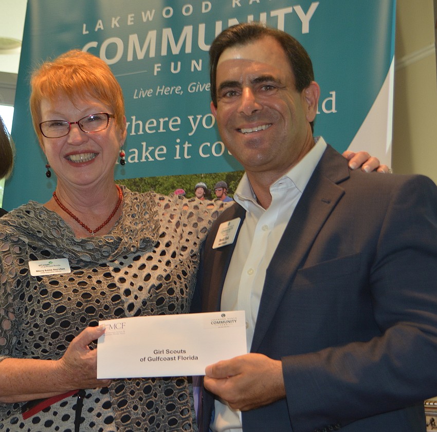 Mary Ann Servian, the CEO of the Girl Scouts of Suncoast, receives a grant for $2,000 from board member David Fink.