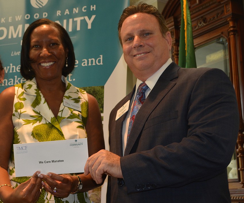 Victoria Kasdan, the executive director of We Care Manatee, receives a grant of $5,000 from board member Chris Romine.