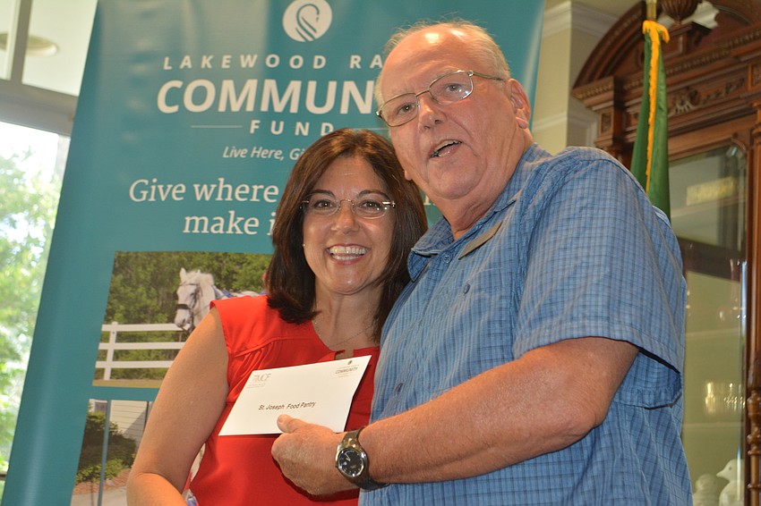 Board member Lori Ruth hands Roger Brown of the St. Joseph Food Pantry a check for $2,000.
