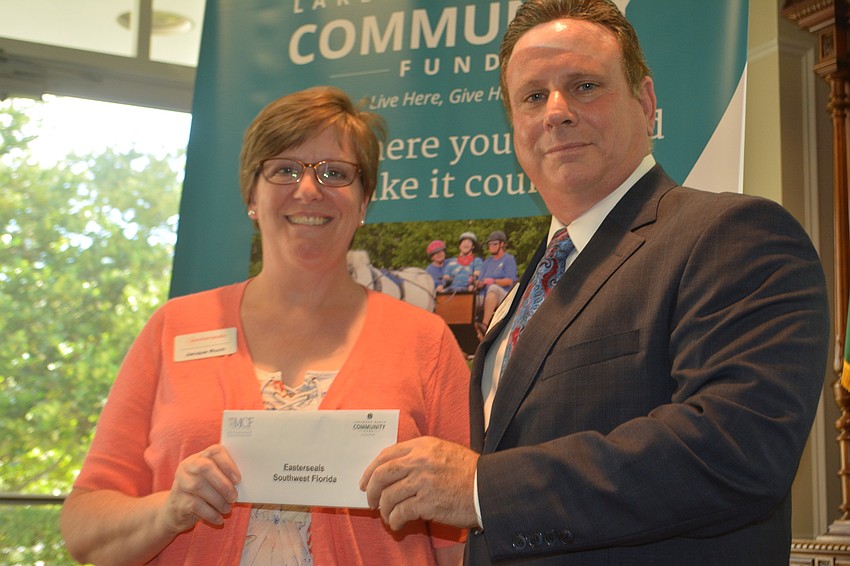 Jacque Ruch, the vice president of programs for Easterseals Southwest Florida, receives a grant for $5,000 from board member Chris Romine.