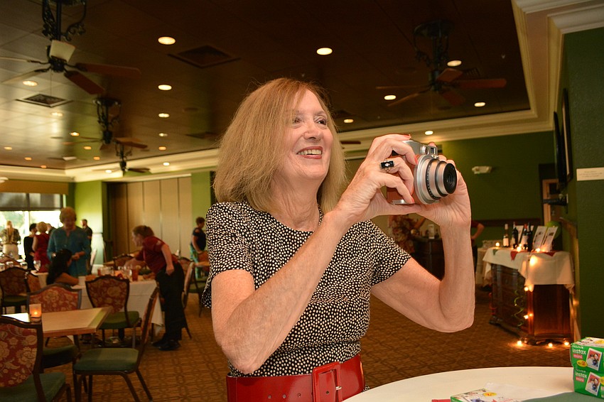 Janet Goldberg snaps Polaroid photos of guests in front of picture of an Italian building.