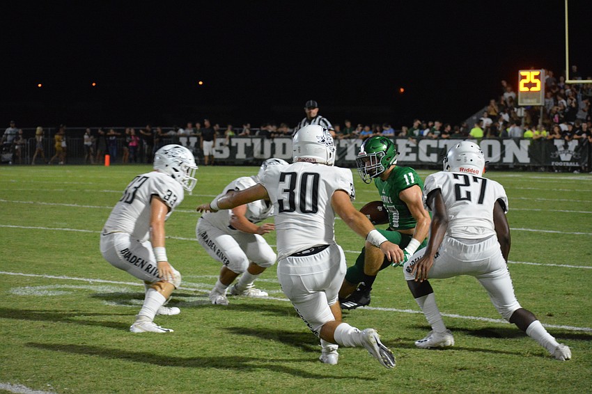 A crowd of Pirates, including senior linebackers Jackson Dietz (33), John Dipasqua (30) and Cobee Crawford (27), wrangle a Venice punt returner for minimal gain.