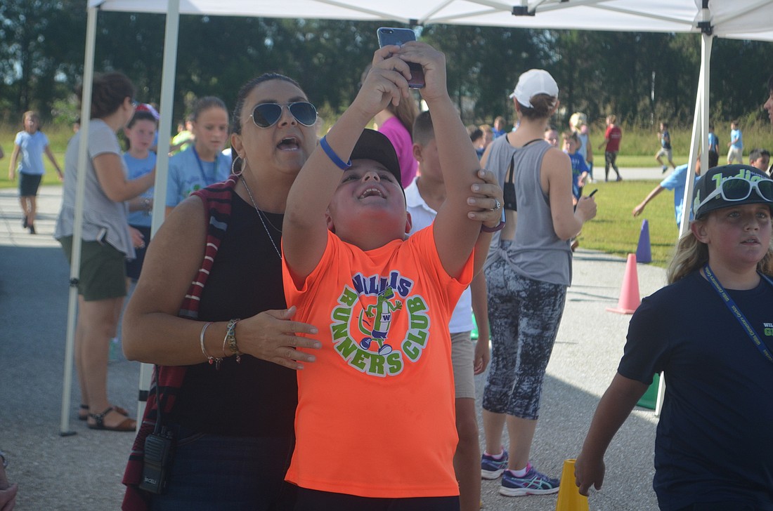 Maria Micelli and her fifth-grade son, Christian Micelli snap a quick picture before Christian Micelli keeps jogging around the track during the walkathon.