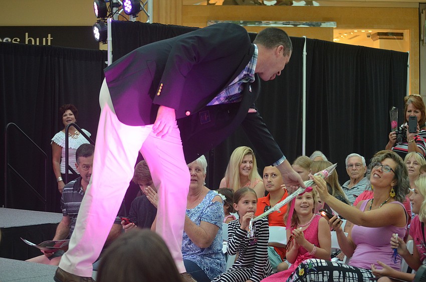 Joe Ernst, with D&D Garage Doors and Manatee Sarasota Building Industry Association, hands a flower to his wife Erin Ernst and says that he walks the runway because he likes being able to raise awareness for the cause.