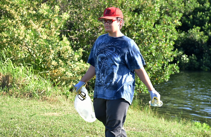 Joseph Ganpat carries an old water bottle while cleaning up City Island.