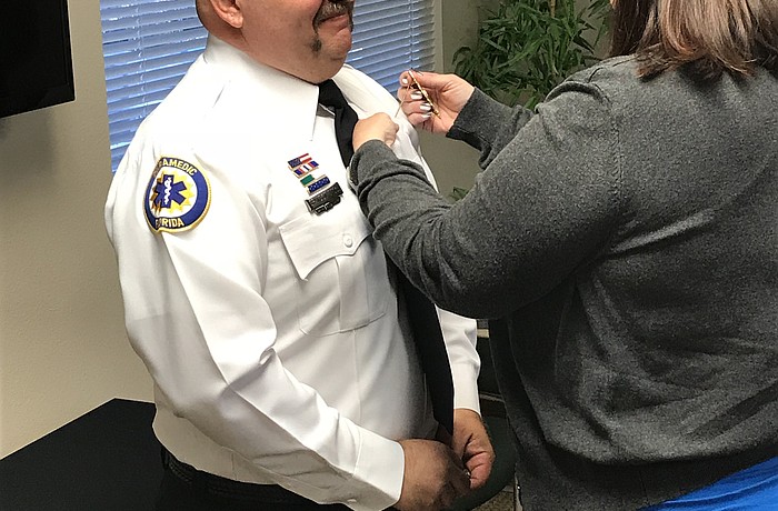 Rebecca Desch pins the lieutenant insignia on the shirt of her husband, Brandon.