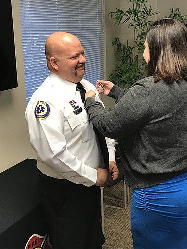 Rebecca Desch pins the lieutenant insignia on the shirt of her husband, Brandon.
