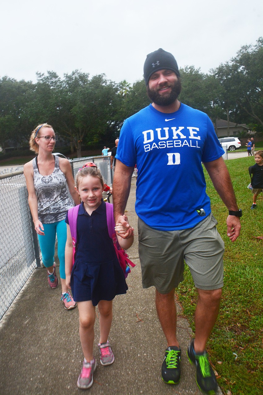 Darren Brunner walks with his first-grade daughter, Marla, as his third-grader, Ryelynn, runs ahead.