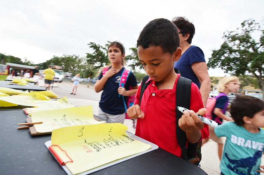 Second-grader Noah Holland checks in after walking to school. He signs his own name.