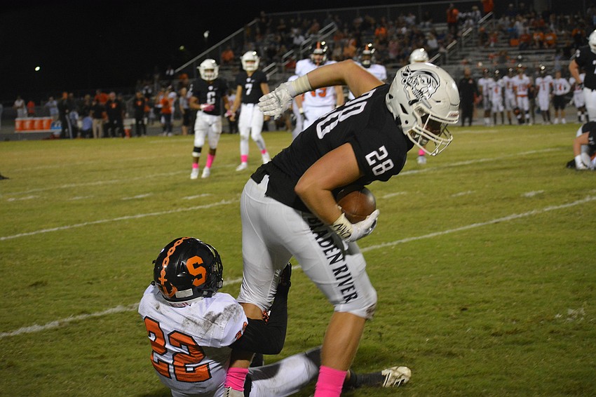 Sarasota junior safety Jason Scott (22) wraps up Pirates junior tight end Travis Tobey (28).