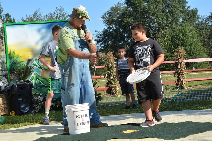 Bradenton's Josiah Estevez, in black, successfully jumps a frog 154 inches in the frog jumping contest. He avoided touching the creature, though.