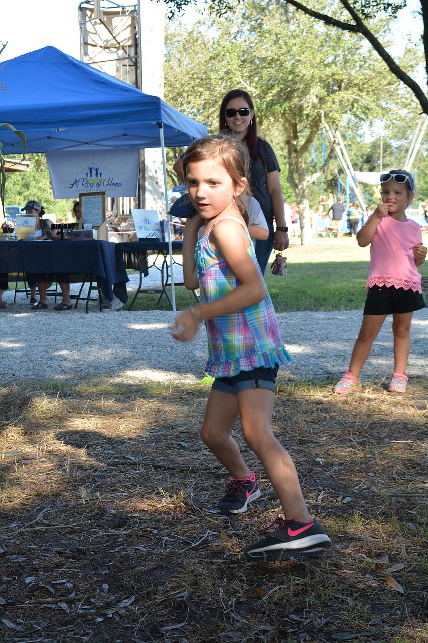 Fort Myers resident Leah Benoit, 5, plays corn hole, one of the pumpkin charity games.
