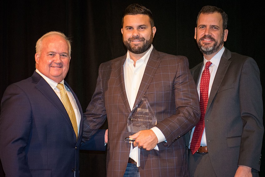 Joe Seidensticker accepts the Chair's Cup Award from Rob Lane and Charlie Bailey on behalf of his father, Steve.