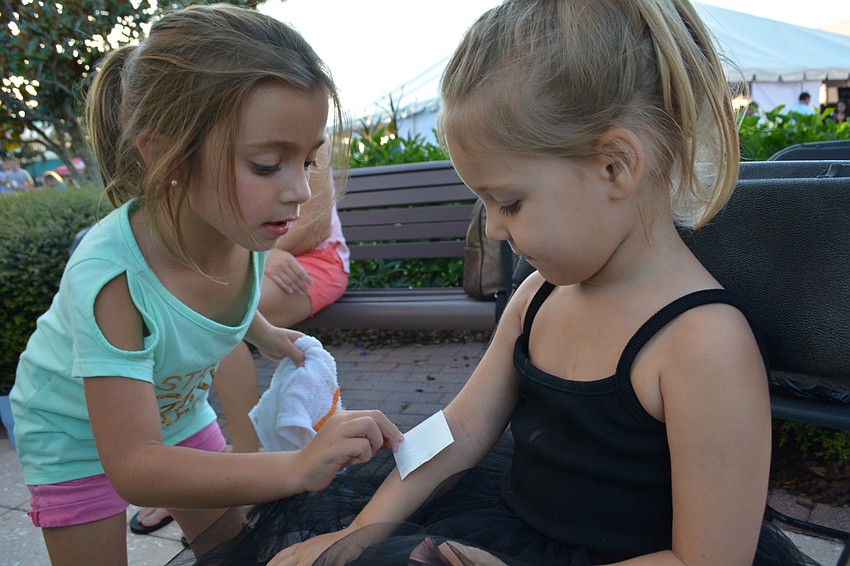 Through the volunteer group Sugar, 5-year-old Carly Guido puts a heart tattoo on the arm of 3-year-old Hadley Shaw.