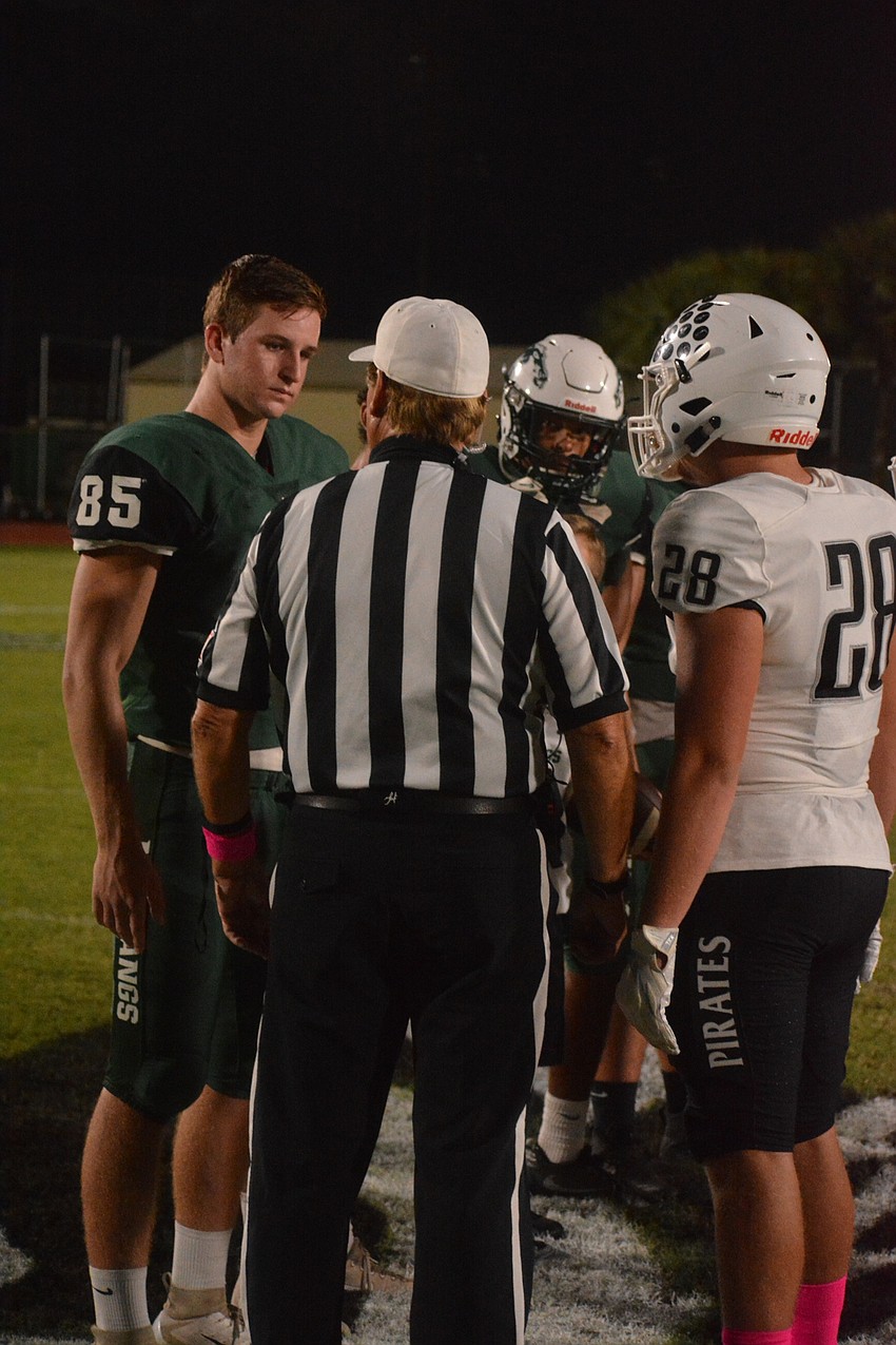 Mustangs senior Drake Theriot (85) and Pirates junior Travis Tobey (28) talk with the referees before the coin toss.