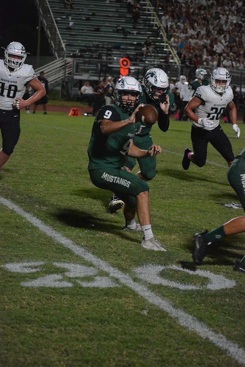 Mustangs senior QB George Davis pitches to junior Gavin Goeden on an option play.