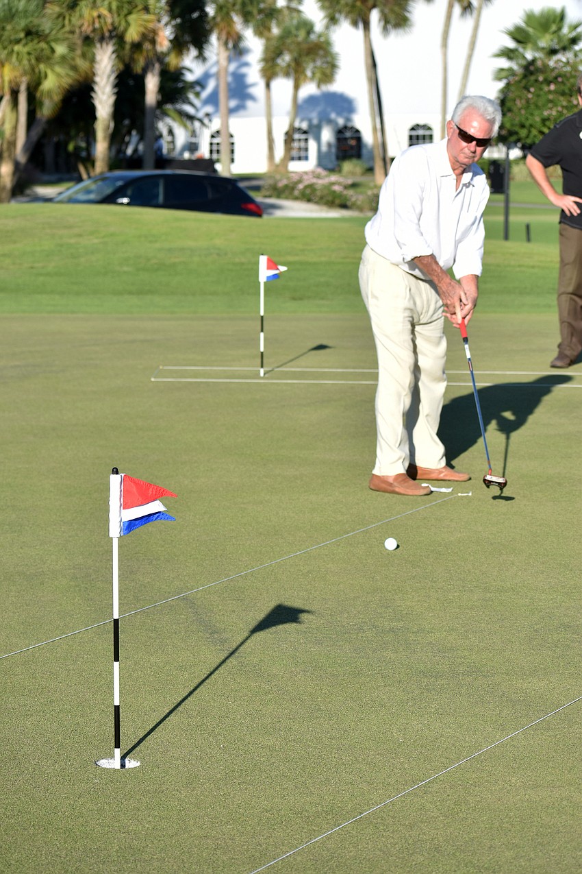 Commissioner Jim Brown watches the golf ball roll toward the hole following his putt.