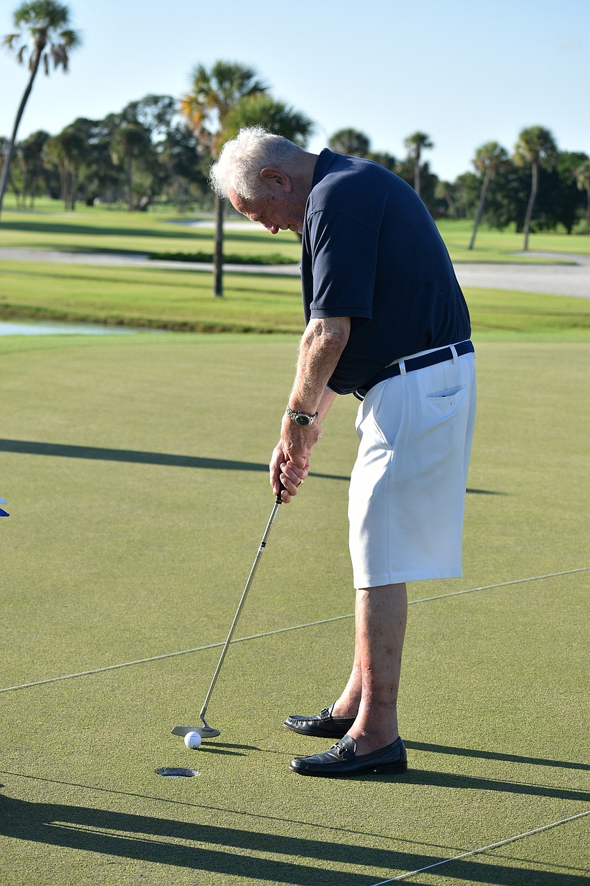 Mayor George Spoll taps the ball into the hole.