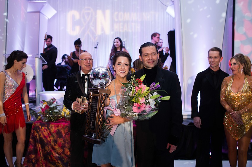 Monica Kelly smiles for photos with her trophy and dance partner.