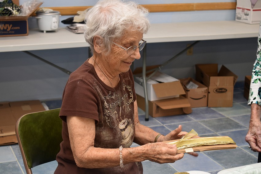 Stella Kelley measures a piece of ribbon to be used to decorate a piece of swag.