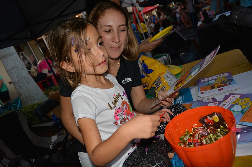 Lakewood Ranch 5-year-old Carly Guido helps Jen Mackey, of Budget Blinds, pass out candy, coloring books, Frisbees and bags.