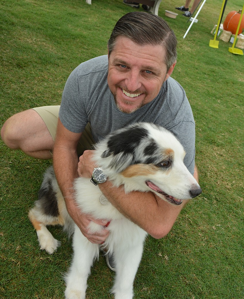 Larry Cavalluzzi, who had a booth at Barctober Fest with his Salty Printing company of Bradenton, gives Savannah, an 8-year-old Australian Shepherd, a hug.