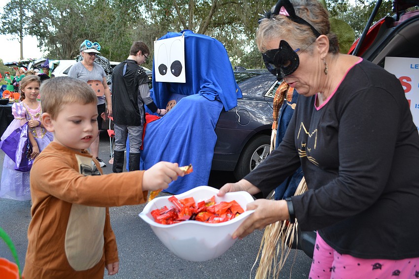 Four-year-old Hayden Hall collects candy from cat, better known as Beth Long.
