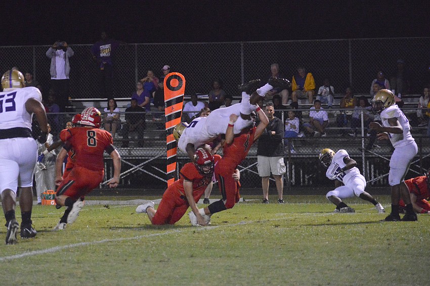 Cardinal Mooney senior Sam Koscho (4) lifts a Booker runner into the air for the tackle.