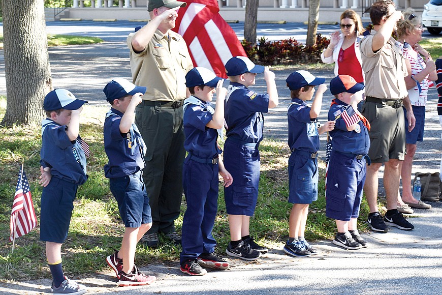 Boy Scouts salute veterans as they pass them on the parade route.
