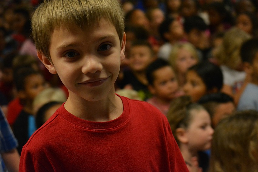 Peyton Painter is all smiles as he and other fourth-graders pile on to the stage.