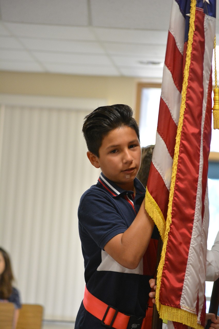 Fifth-grader Aurelius Pena presents the colors to lead off the presentation.