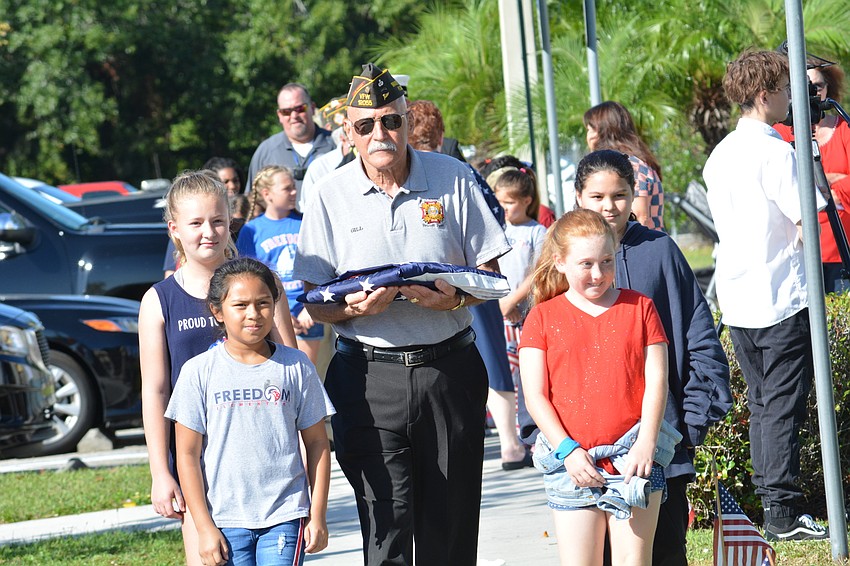 VFW Post 12055's Gill Ruderman, center, carries the American flag to be raised in the courtyard. He is helped by (clockwise from front left) Abygail Jimenez, Briley Fleeman, Jessica Enchautegui-Mauldin and Olivia Michaels.