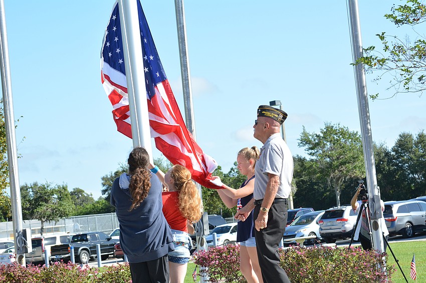 VFW Post 12055 veteran Gill Ruderman raises the American flag with the help of Freedom students in the school's courtyard.