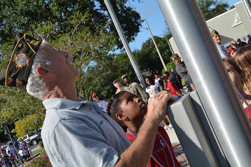 VFW Post 12055 member Charlie Busack, a Vietnam veteran, raises the U.S. Air Force flag in the courtyard with the help of students Naomi Geffrard and Kailen Monceaux (not pictured).