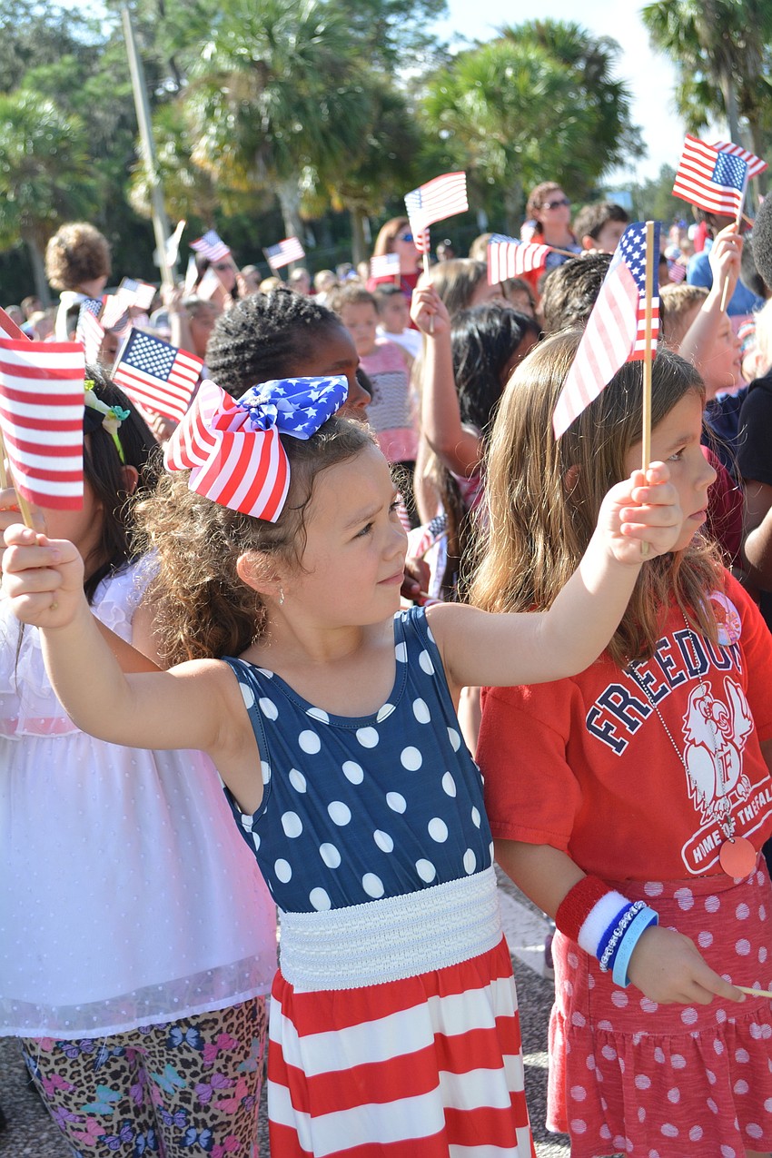 Kindergarten student Jalee Harnish proudly waves her flag during a post-ceremony song.