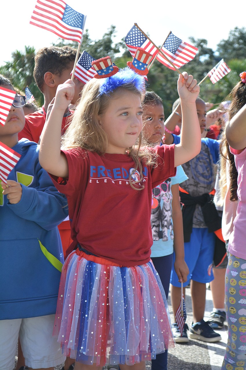 Five-year-old Abigail Carlisle waves American flags during a song to conclude the ceremony.