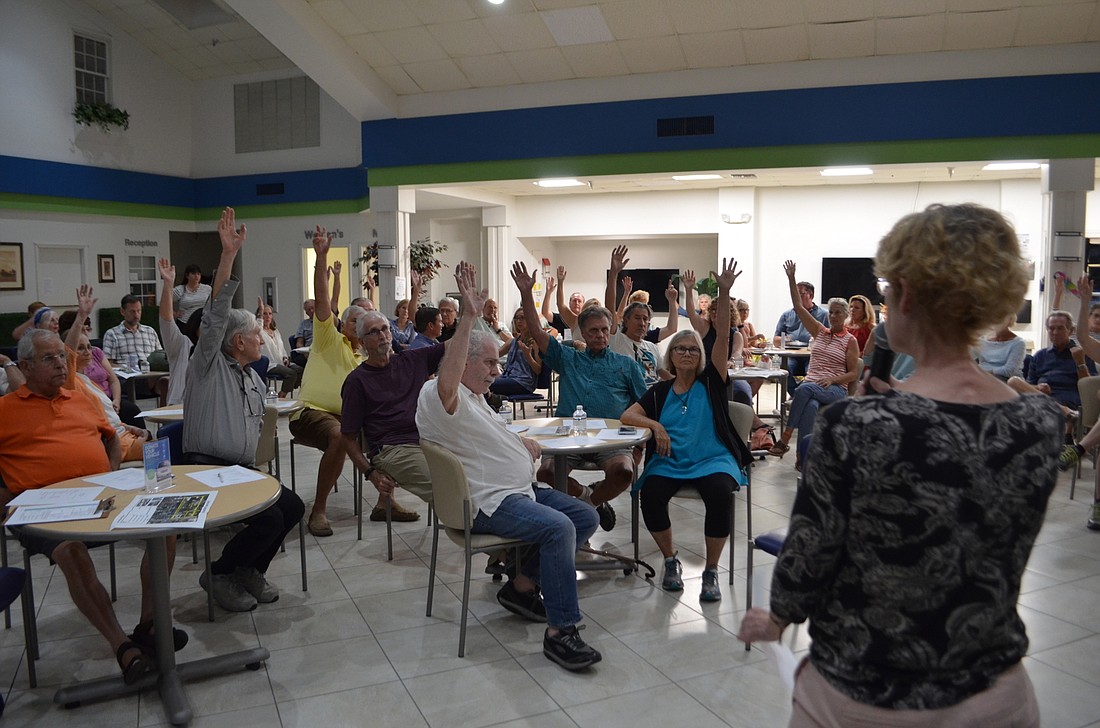 Laurel Park residents raise their hands to show their opposition to the proposed zoning changes in the form-based code.