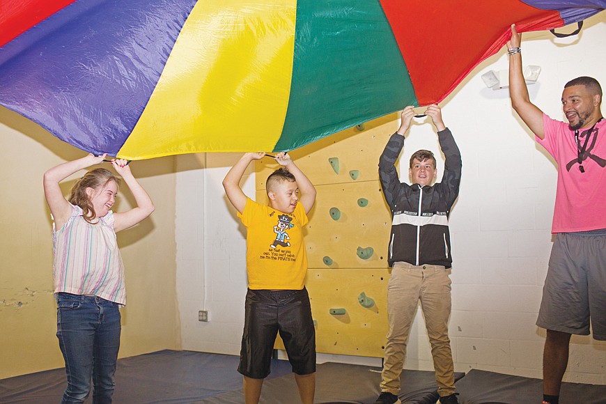 Athletic Director David Gaulman (right) and eighth-grader Dusty Wilson (second from right) lead Melody Wells and Jose Enriquez, students in the schoolâ€™s Mariposa program, through a parachute exercise.
