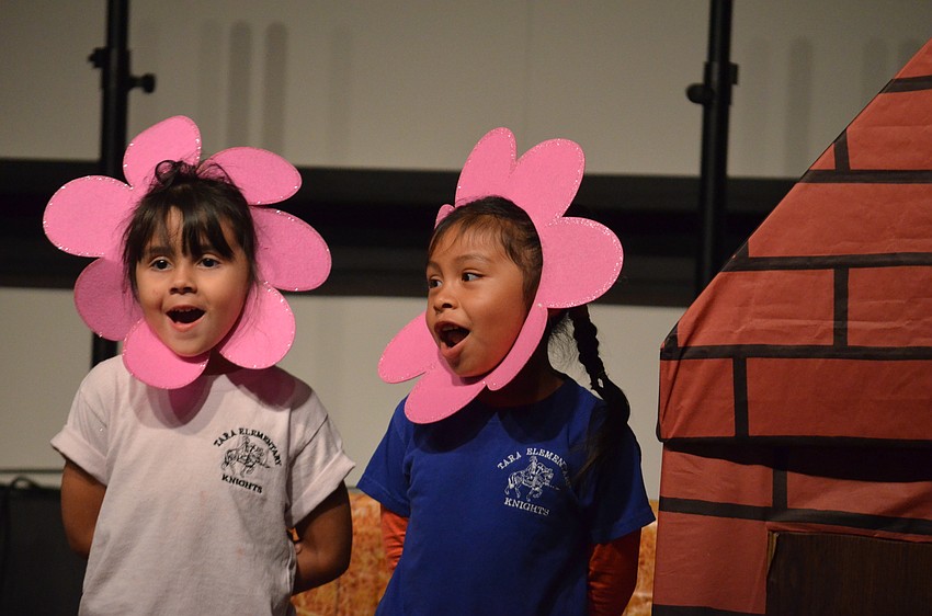 Stella Odom and Melani Enriquez play two of the flowers just outside the brick house in “The Three Little Pigs” presentation. They sang “Who’s Afraid of the Big Bad Wolf.”