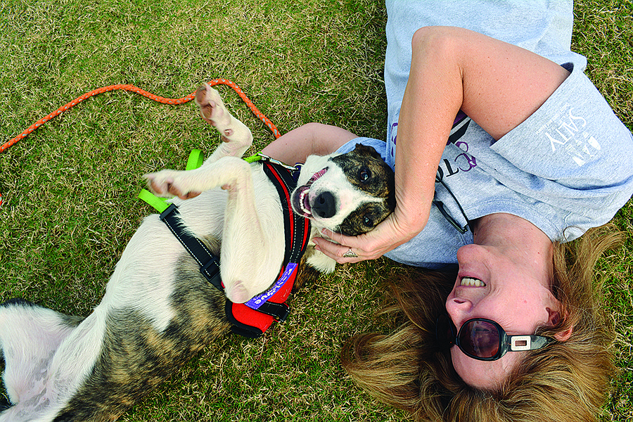 Lakewood Ranchâ€™s Kelly Taylor, an ARC volunteer, rolls on the ground with Ellie May, a 1-year-old basenji-bull terrier mix.