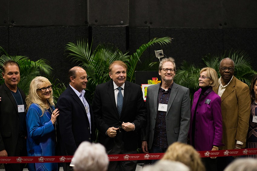 The ribbon cutters laugh and smile before cutting the ribbon.