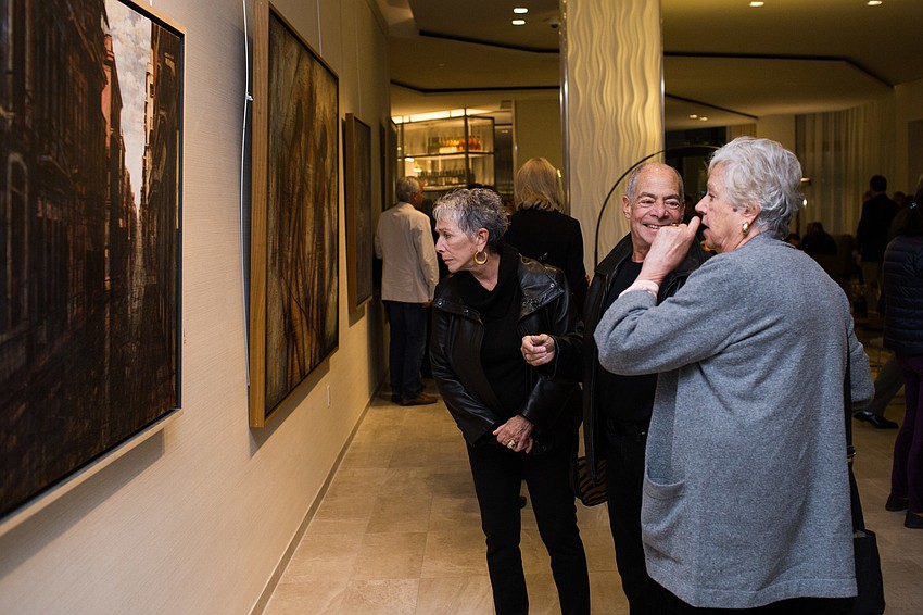 Guests smile as they view the pieces on the walls.