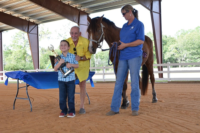 SMART Rider Cooper Vollmer accepts the Kathy Logli Memorial Award for Excellence from Peter Logli and SMART instructor Samantha Toomey and horse, Salsa Baby.