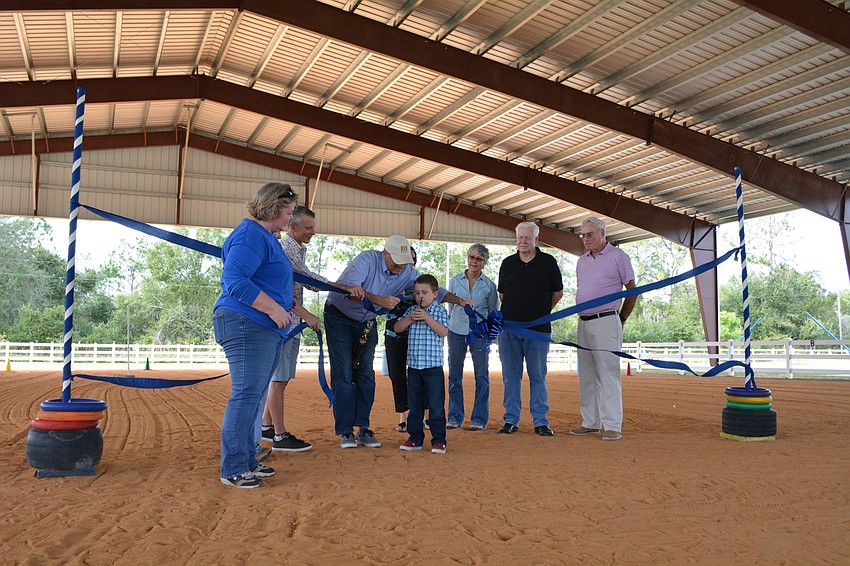 SMART rider Cooper Vollmer gets help from SMART board member Nick Drizos in cutting the ceremonial ribbon.