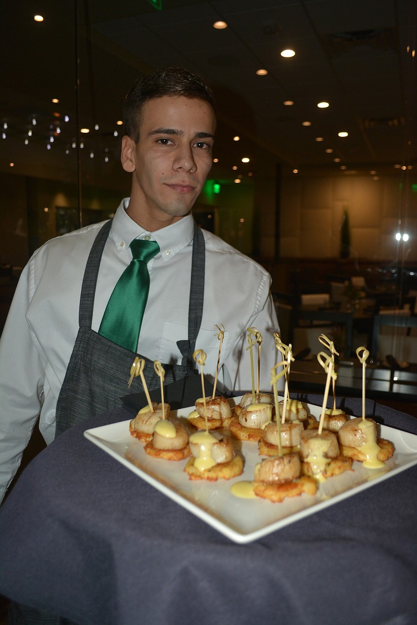 Waiter Roberto Delgado delivers scallops on potato pancakes.