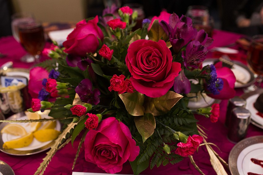 Pink and purple flowers with gold accents adorned the tables.
