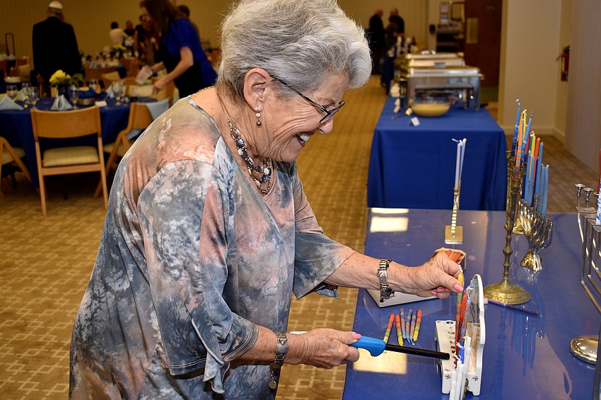 Debby Hamburg lights candles on the menorah she brought to display at the temple.