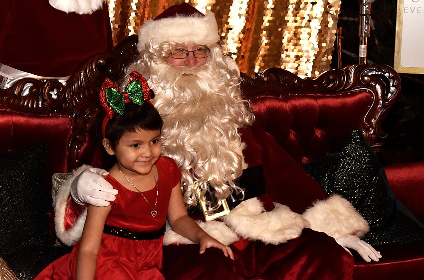 Emma Morales and Santa smile for a photo.