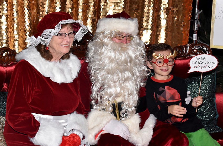 Andrew Naughton uses photo props as he visits with Santa and Mrs. Claus.