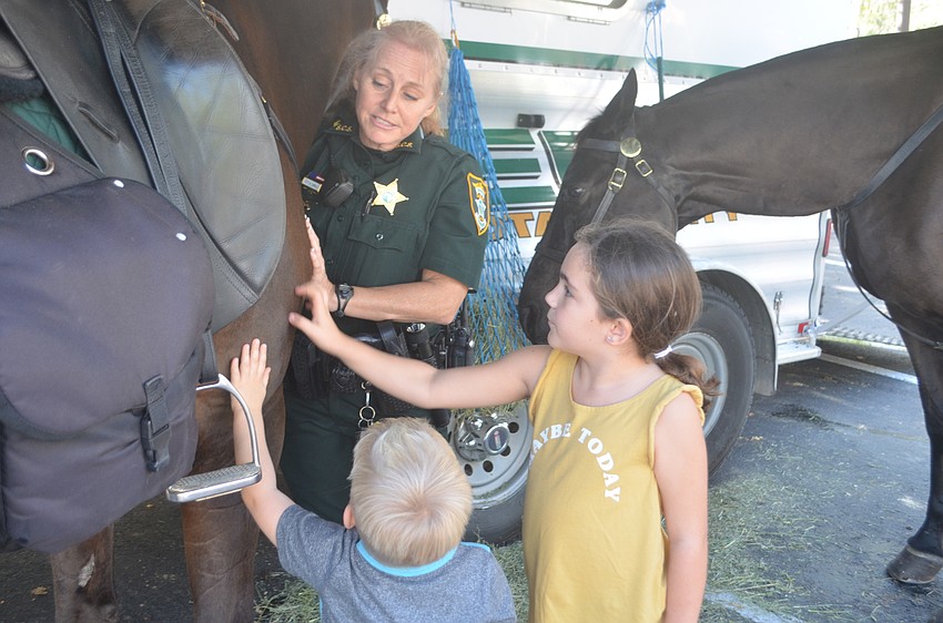 Blake Phelan and Leah Haney pet Valor, a 24-year-old horse handled by Deputy Karla Small.